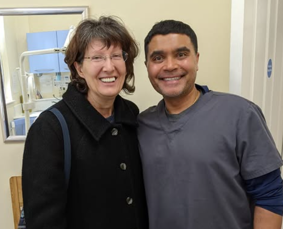 Johnny standing alongside a smiling patient